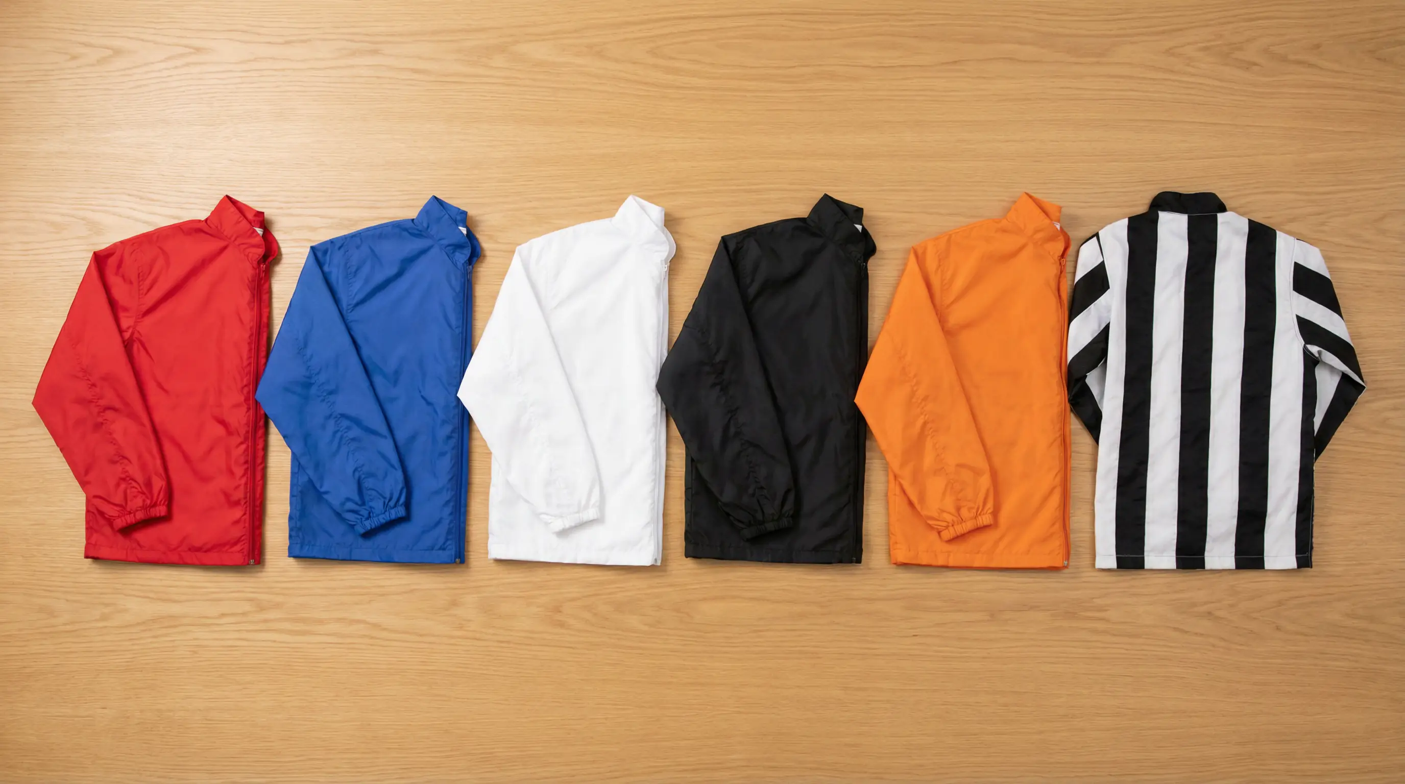 Six greyhound racing jackets in trap colours — red, blue, white, black, orange and striped — laid out in order